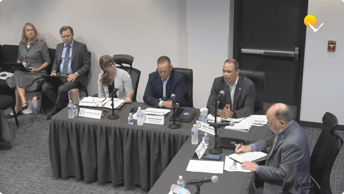 Officials seated at a table with nameplates and microphones during a government budget workshop meeting. Frame from the official Pasco County Government meeting recording at 0:04:53.